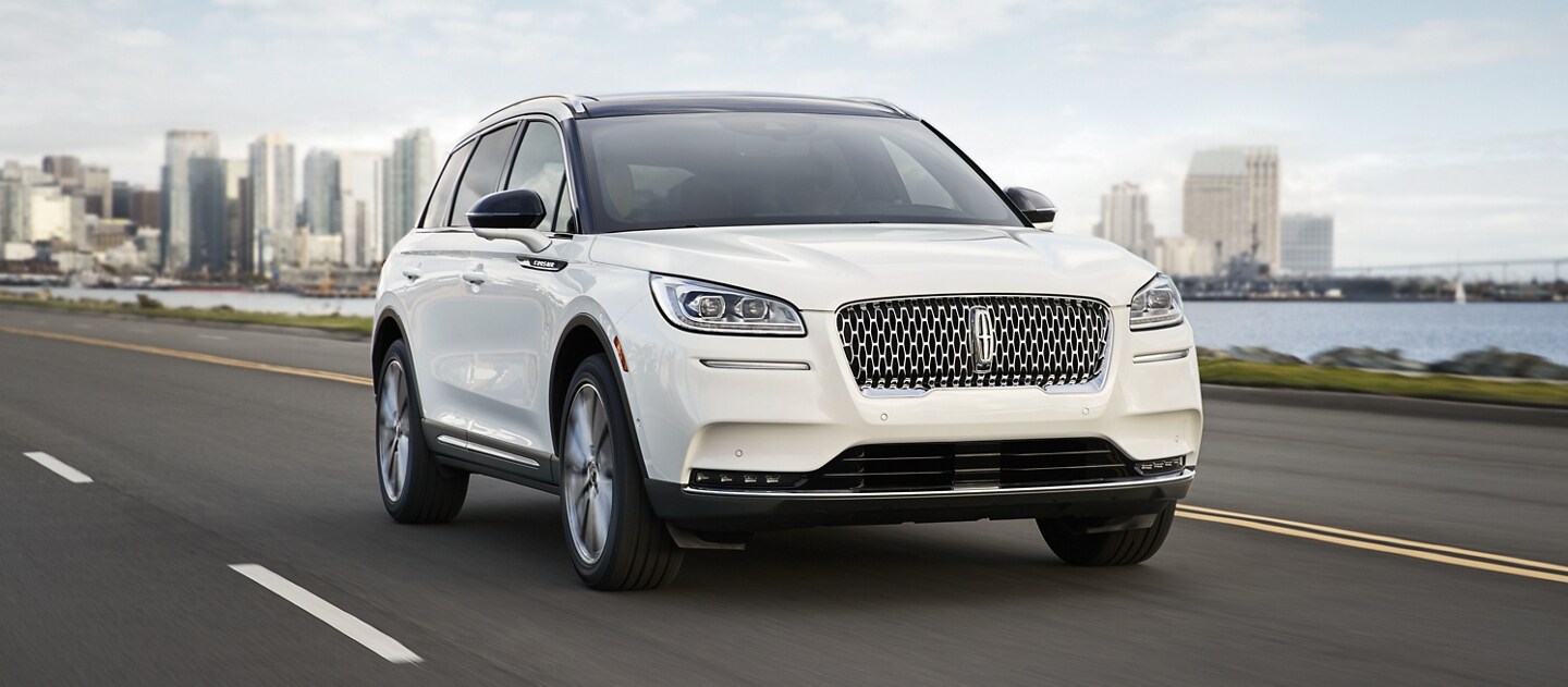 A 2021 Lincoln Corsair in pristine white is effortlessly being driven along a coast using Lincoln Drive modes