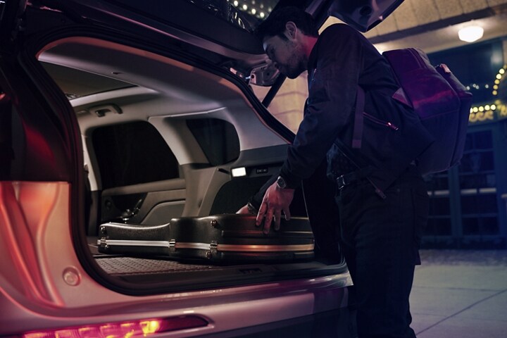 A musician slides his guitar case into the cargo space of a Lincoln Corsair with the rear seats folded flat to provide ample cargo space