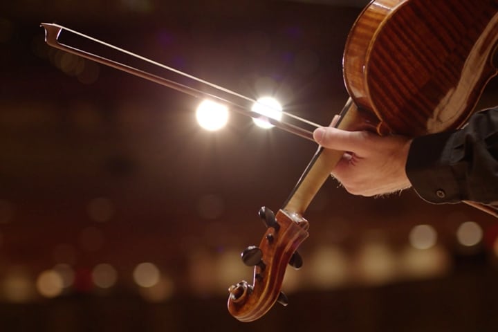 A bow slides across the strings of a violin
