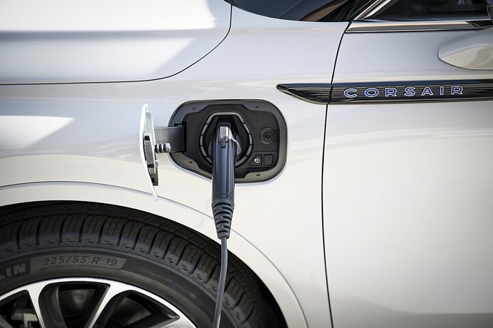 An electric charger is plugged into a 2023 Lincoln Corsair Grand Touring port below the nameplate near the drivers door