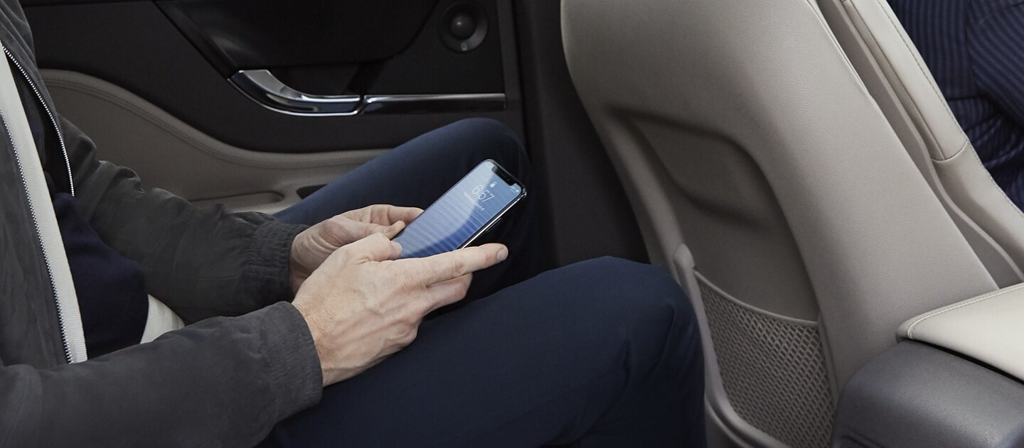 A rear seat passenger of a 2023 Lincoln Corsair SUV uses his smartphone