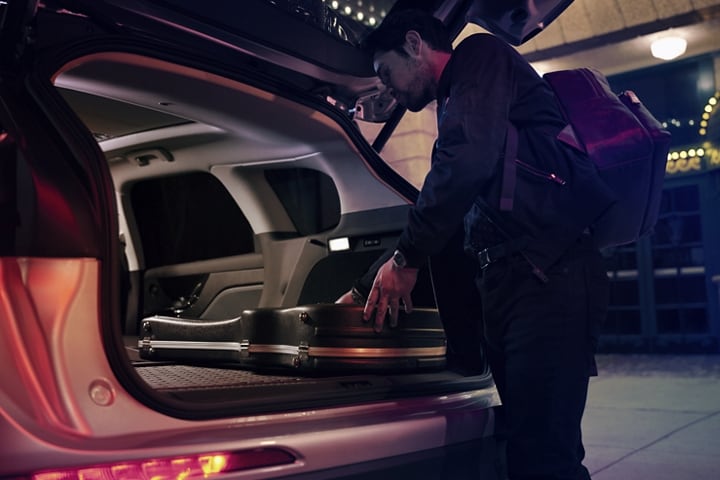 A musician slides his guitar case into the cargo space of a 2023 Lincoln Corsair SUV with the rear seats folded flat