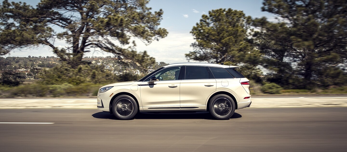 A 2023 Lincoln Corsair Grand Touring is being driven along a coastline with greenery