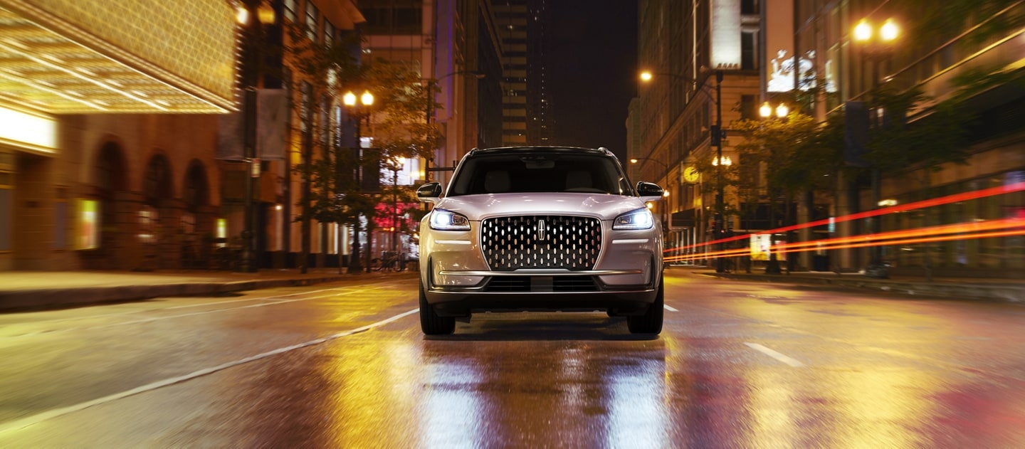 A 2023 Lincoln Corsair SUV is being driven on a city street at night