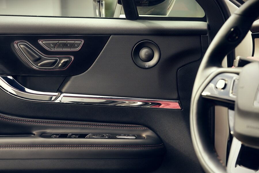 A black Revel® door speaker’s contrasting texture mimics the goosebump raising sensation of the sound system