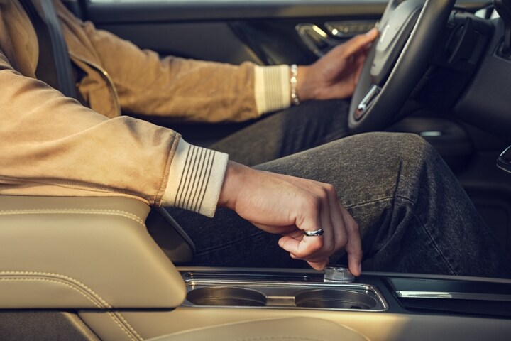 Through an exterior window reflecting surrounding skyscrapers we see a drivers hand turning the Lincoln drive modes knob