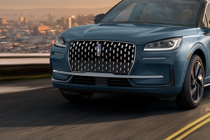 The 2023 Lincoln Corsair Grand Touring grille shows floating chrome ovals that catch the glowing light of a theatre marquee
