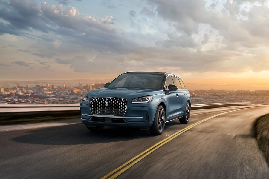 A 2023 Lincoln Corsair Grand Touring model is show being driven on a hillside road.
