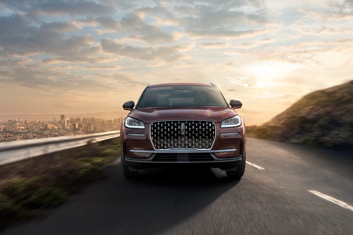 A 2023 Lincoln Corsair SUV is being driven on a sun-drenched road