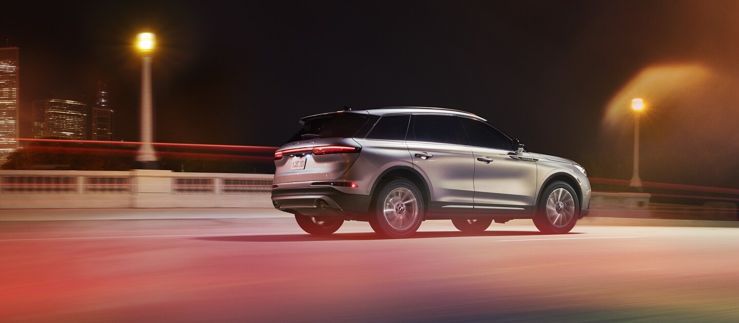 A 2023 Lincoln Corsair SUV is being driven through an urban setting at night