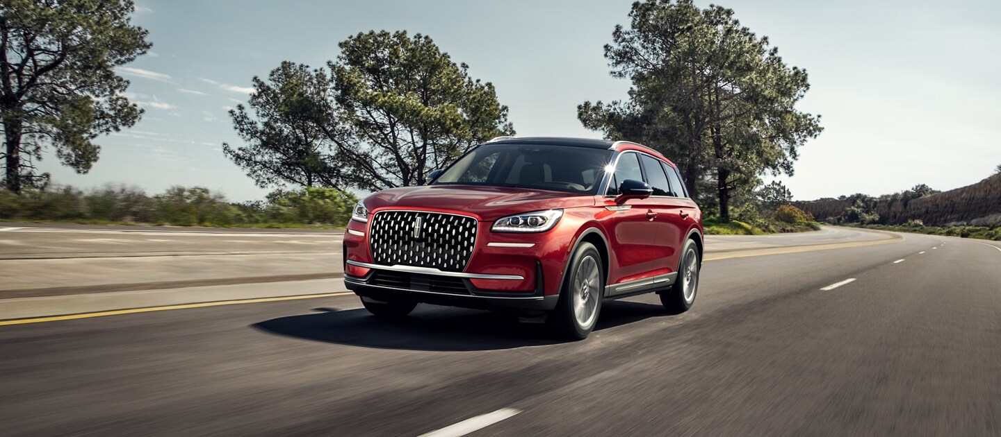 A 2024 Lincoln Corsair is being driven on a tree-lined road