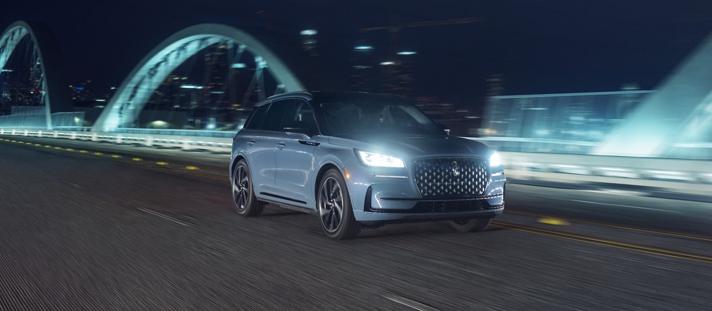 The 2024 Lincoln Corsair SUV drives across an illuminated bridge at night