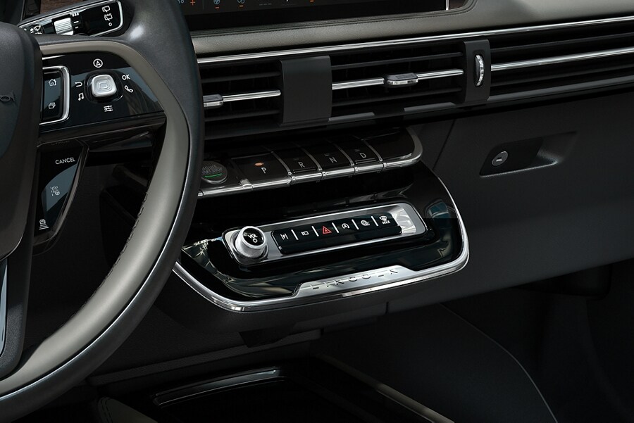 The park button on the elegant piano key shifter is lit up and engaged as light dances off chrome accents and design lines
