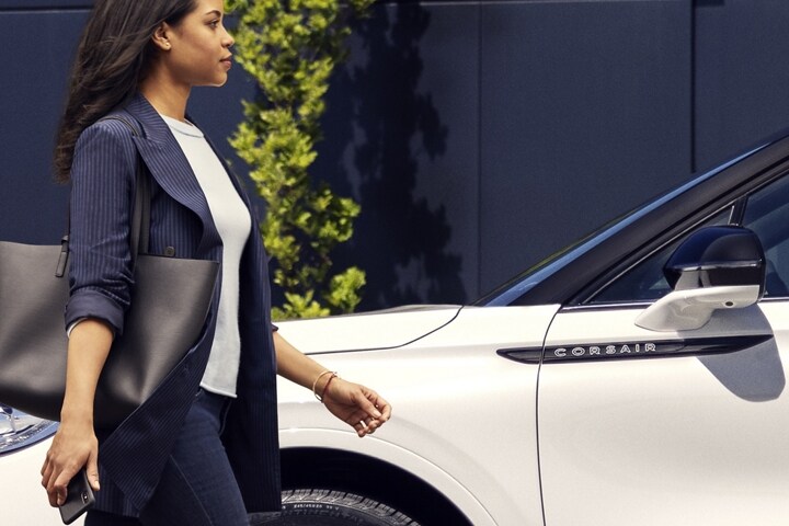 A person approaches a 2025 Lincoln Corsair while holding a mobile phone
