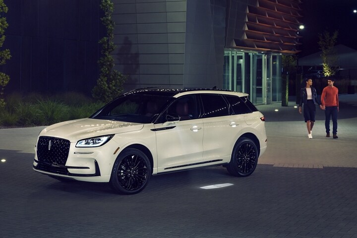 A couple approaches a 2025 Lincoln Corsair as the Lincoln Embrace illumination guides the way