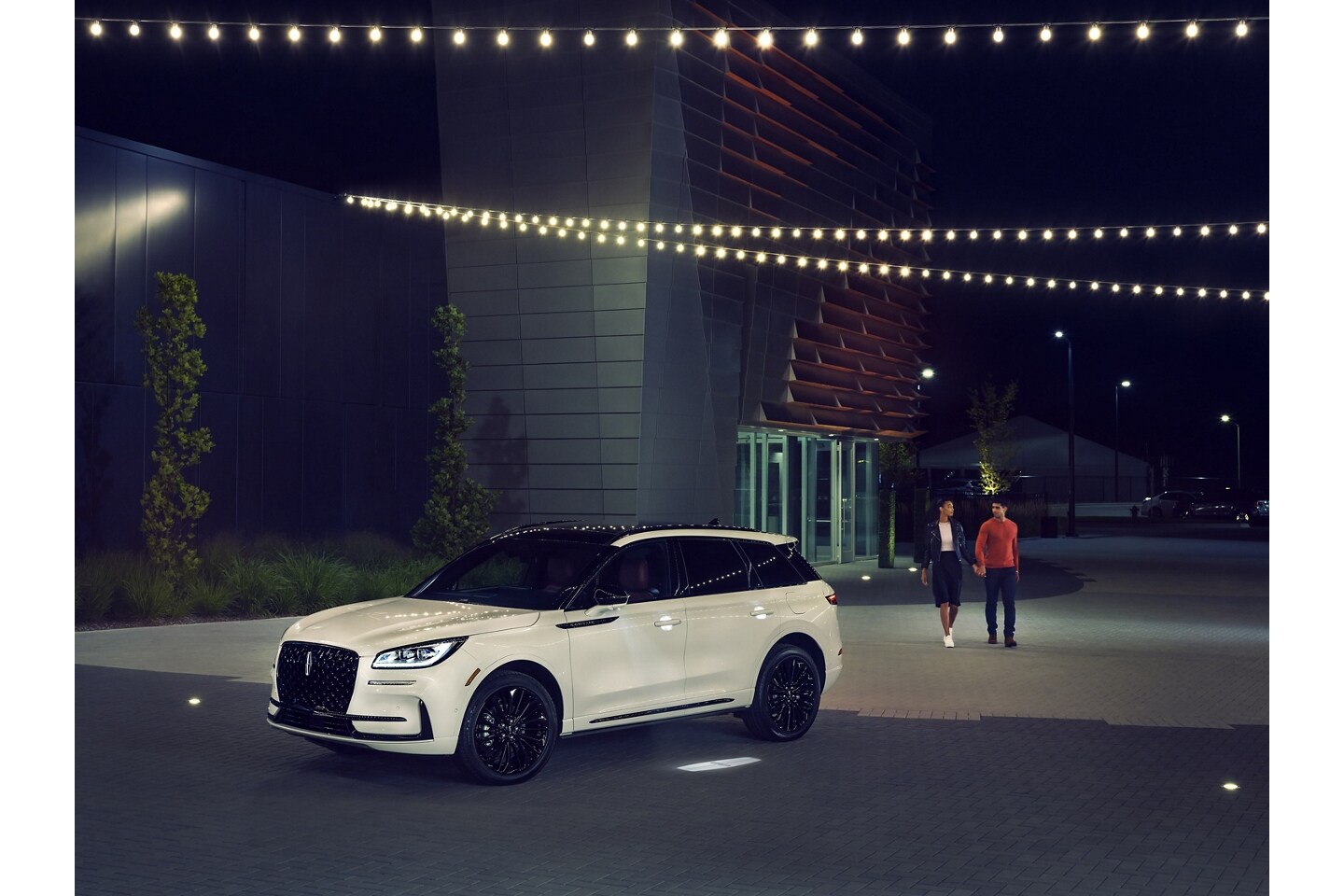 A couple approaches a 2025 Lincoln Corsair as the Lincoln Embrace illumination guides the way