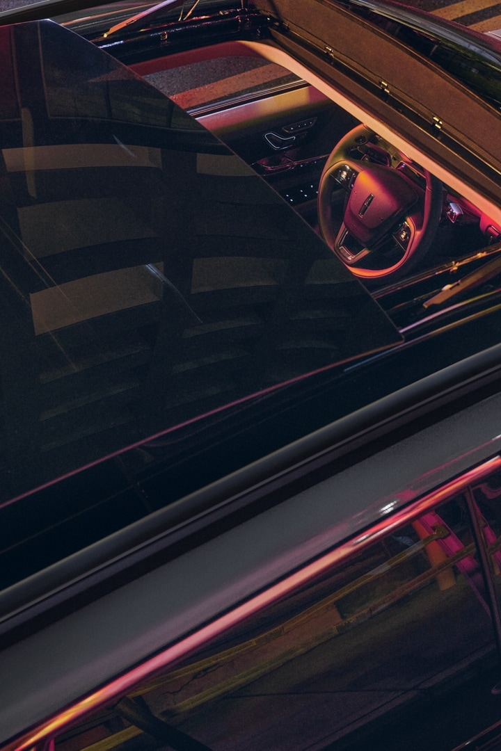 Neon light pours through the available panoramic Vista Roof® of a 2025 Lincoln Corsair