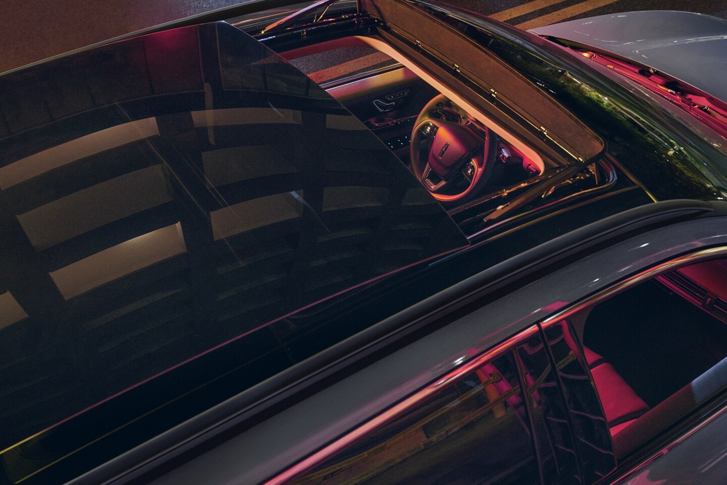 Neon light pours through the available panoramic Vista Roof® of a 2025 Lincoln Corsair