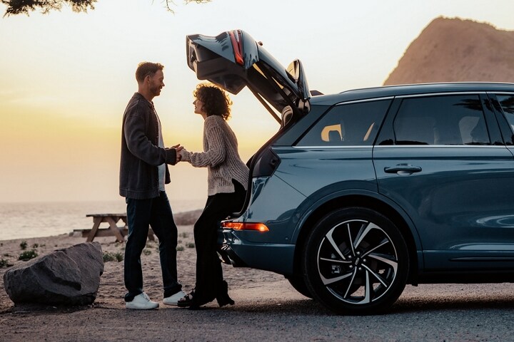 A woman sits in the rear of a 2025 Lincoln Corsair SUV with the rear lift gate open