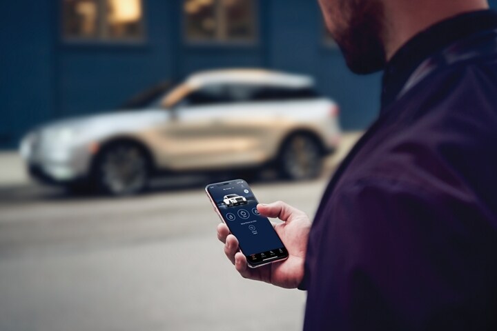 A person uses the Lincoln app to start a Lincoln SUV located across the street