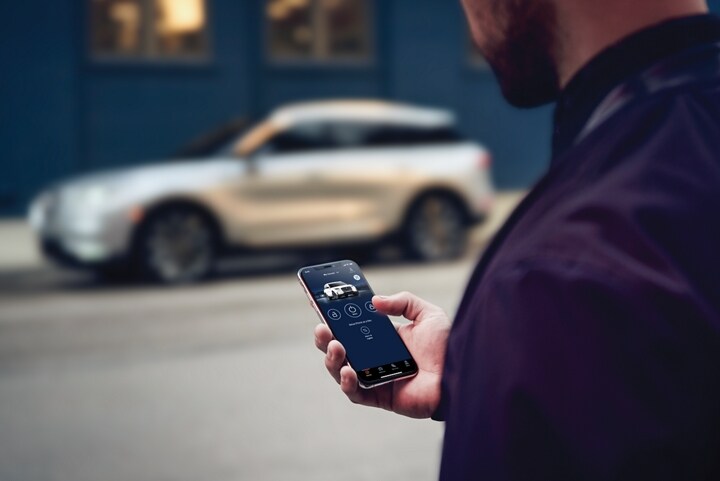 A person uses the Lincoln app to start a Lincoln SUV located across the street