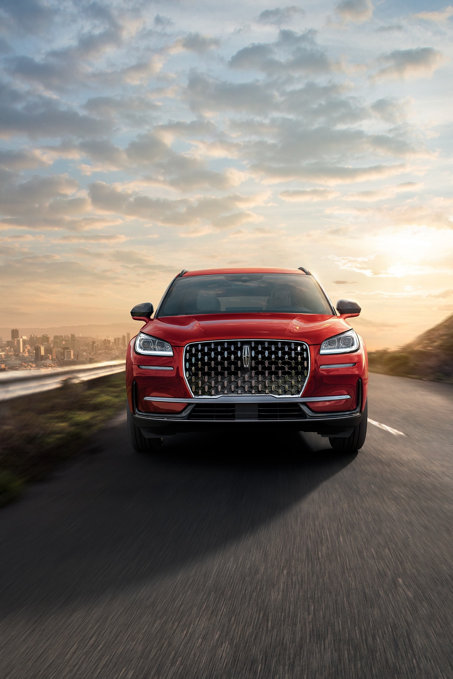 A 2026 Lincoln Corsair Reserve is being driven on a highway with a cityscape in the background