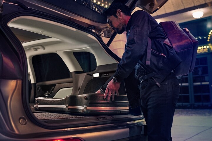 A musician loads musical equipment in the rear cargo area of a 2026 Lincoln Corsair