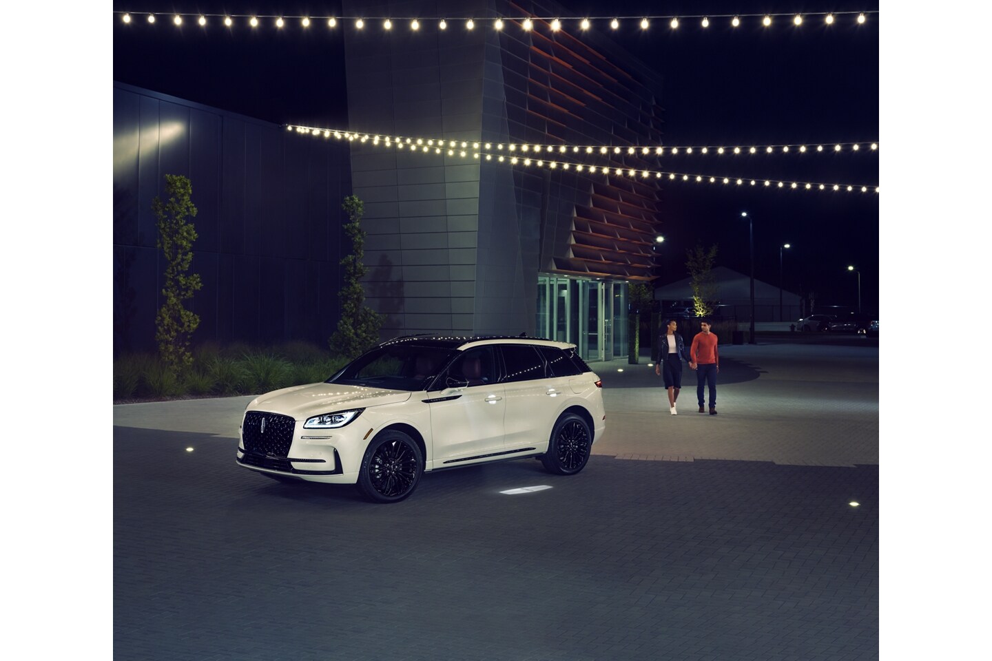 A couple approaches a 2026 Lincoln Corsair SUV as the Lincoln Embrace illumination guides the way