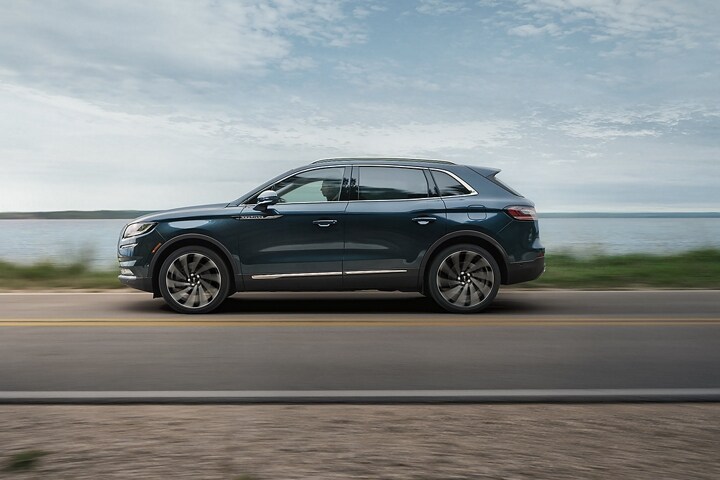 A 2023 Lincoln Nautilus Reserve SUV is shown being driven near a lake