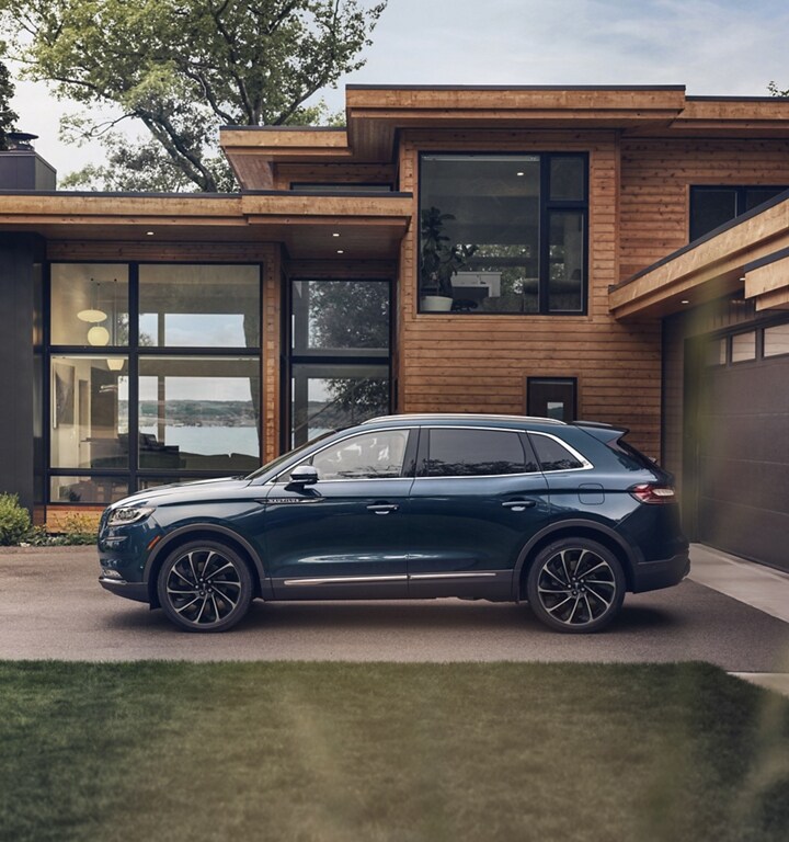 A 2023 Lincoln Nautilus Reserve in Flight Blue is parked outside a modern lakehouse