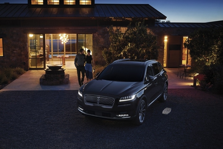 A couple approaches a 2023 Lincoln Nautilus SUV at night