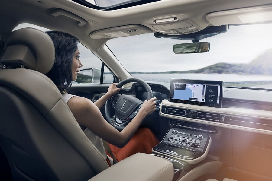 A woman is driving a 2023 Lincoln Nautilus as the navigation application on the center touchscreen guides her course