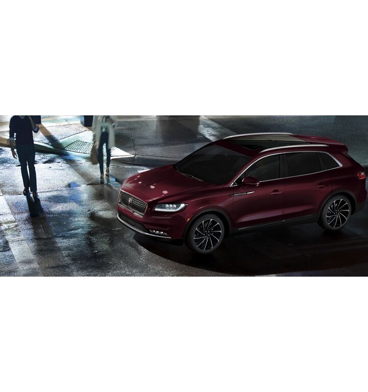 Pedestrians use a crosswalk in front of a 2023 Lincoln Nautilus SUV