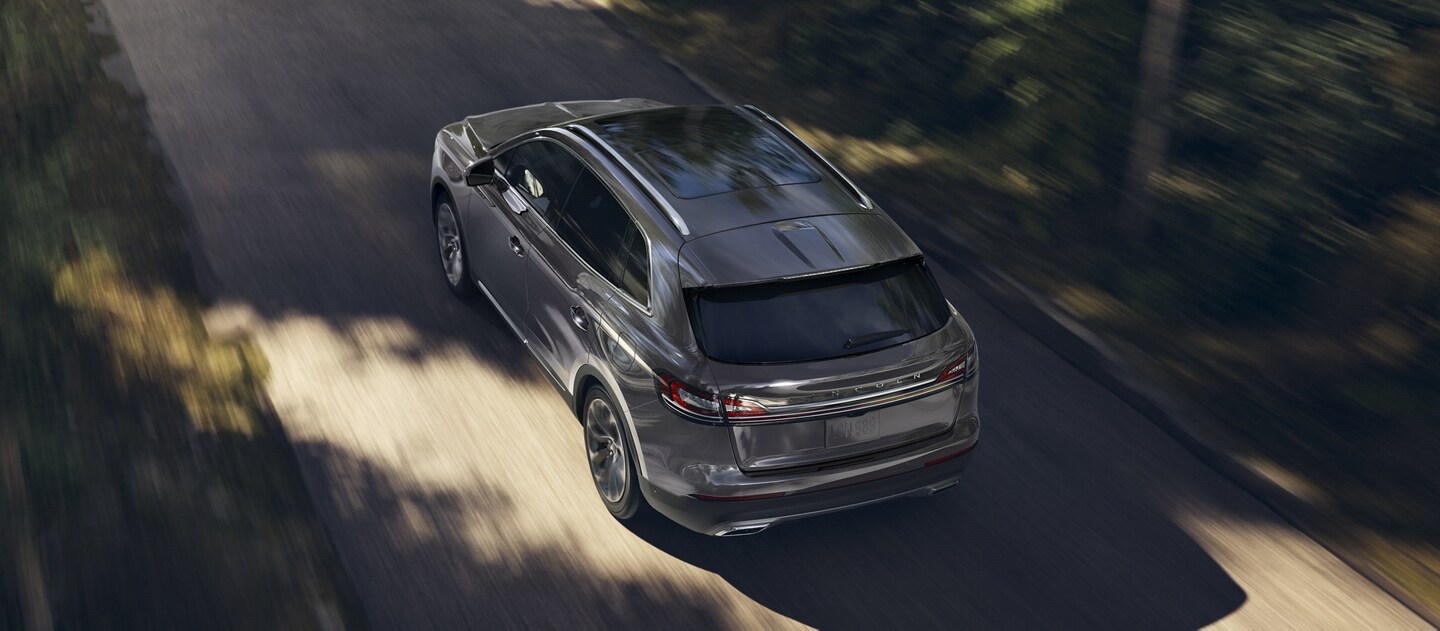 A 2023 Lincoln Nautilus is being driven on a tree-lined road
