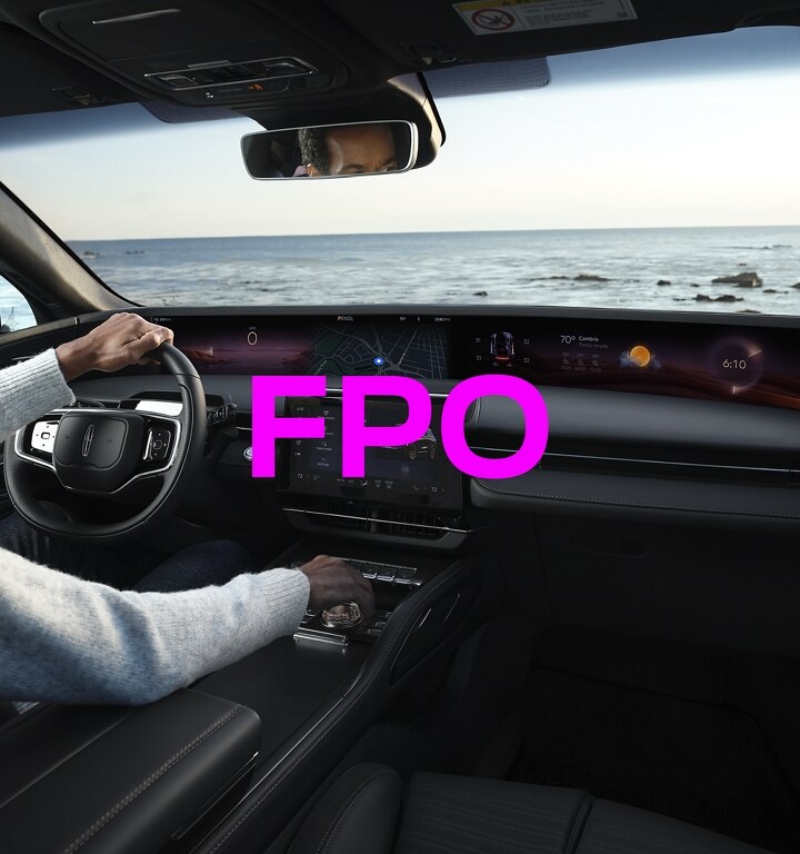 A peaceful evening scene at the coast is shown through the windshield of a 2024 Lincoln Nautilus SUV