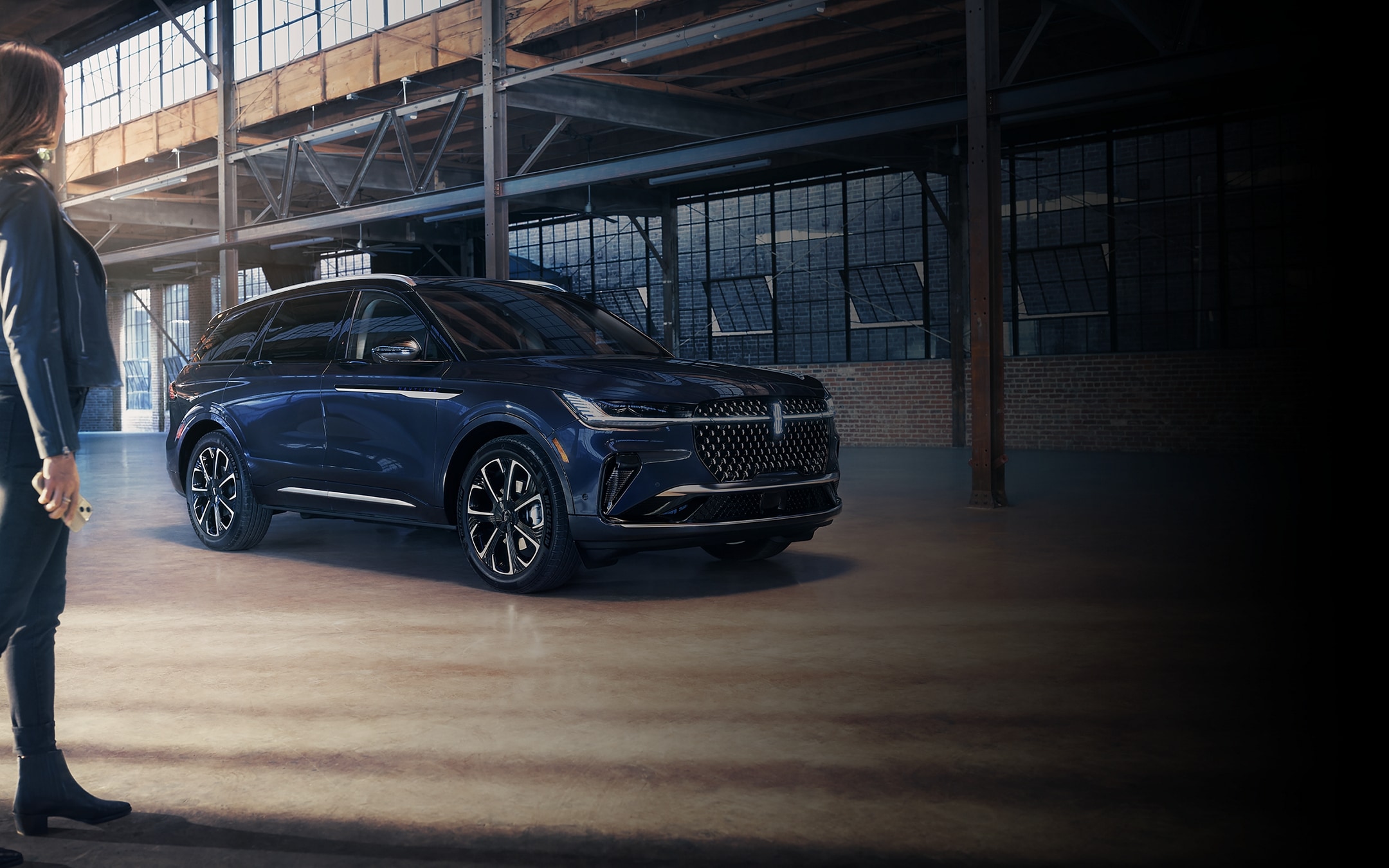 A woman is seen near a 2024 Lincoln Nautilus SUV as the Lincoln Embrace lighting sequence takes place