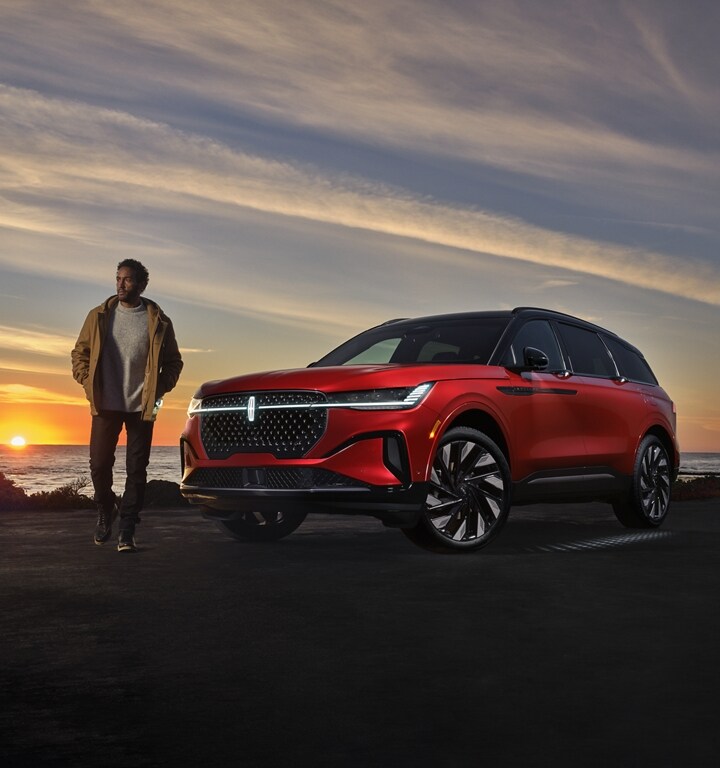 A person is leaving a 2024 Lincoln Nautilus SUV as the Lincoln Embrace lighting sequence illuminates