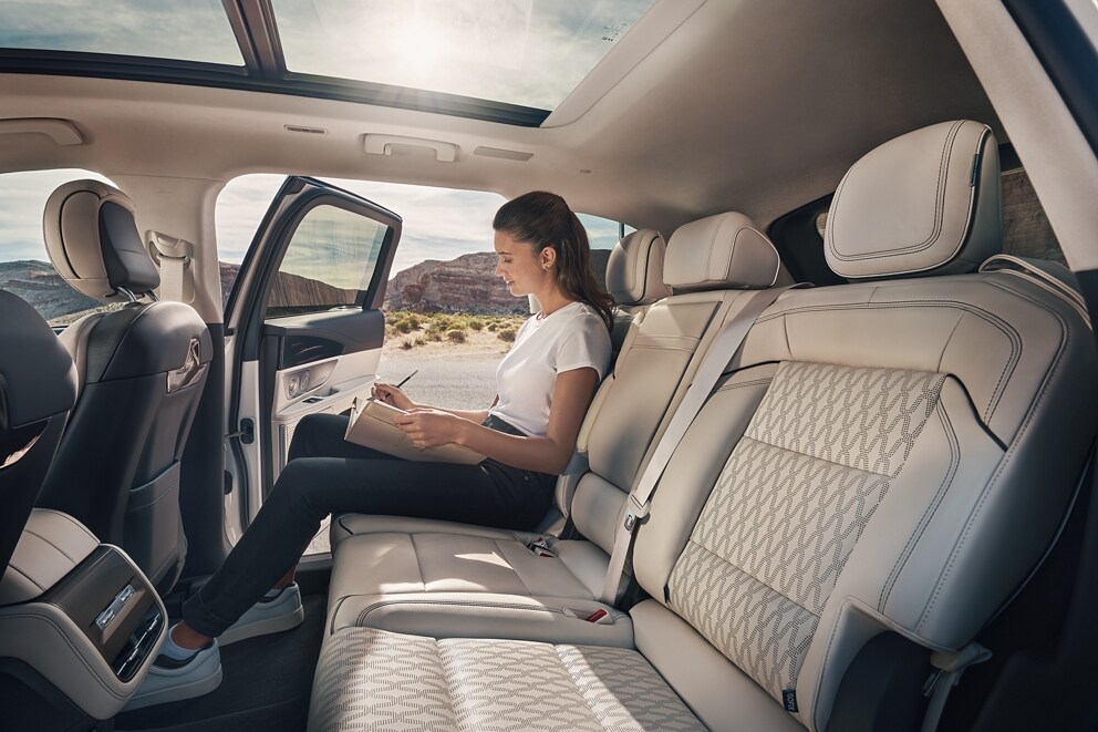 A person takes a relaxing moment in the second row of a 2025 Lincoln Black Label Nautilus SUV