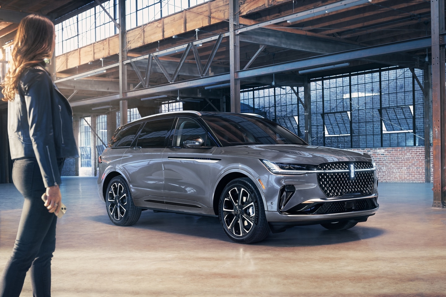 A smartphone is being held in a woman's hand as she walks toward a 2025 Lincoln Reserve Nautilus