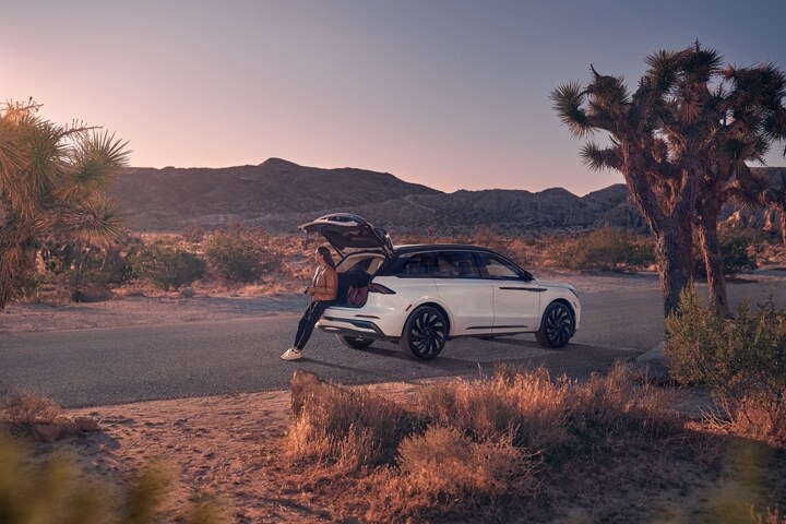 A woman sits on the edge of the rear cargo area of a 2026 Lincoln Nautilus
