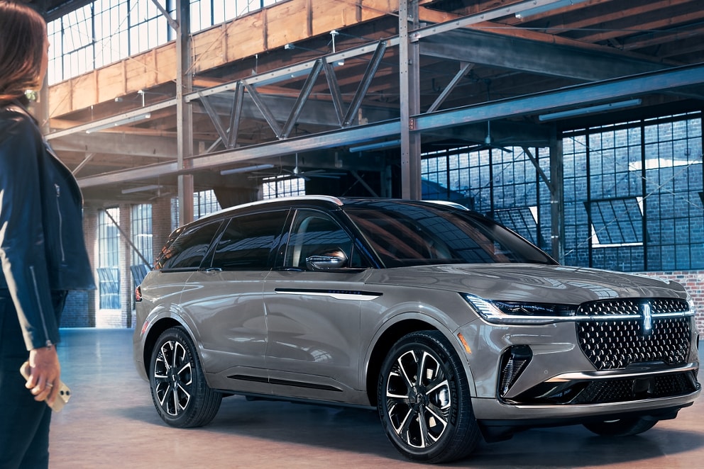 A woman approaches a 2026 Lincoln Nautilus while holding a mobile phone