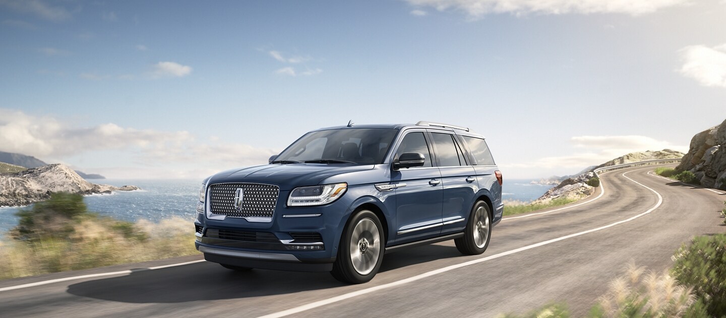 A 2021 Lincoln Navigator in Blue Diamond Metallic is being driven down the sloping coast of a sunny sea side destination