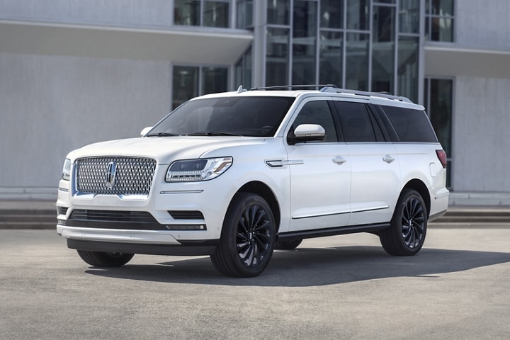 A 2021 Lincoln Navigator Reserve model in the available Pristine White Monochromatic Package parked in front of a building