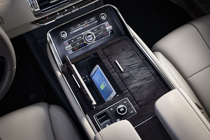 A smartphone is charging on the wireless charging pad that is tucked in a cubby integrated into the front centre console