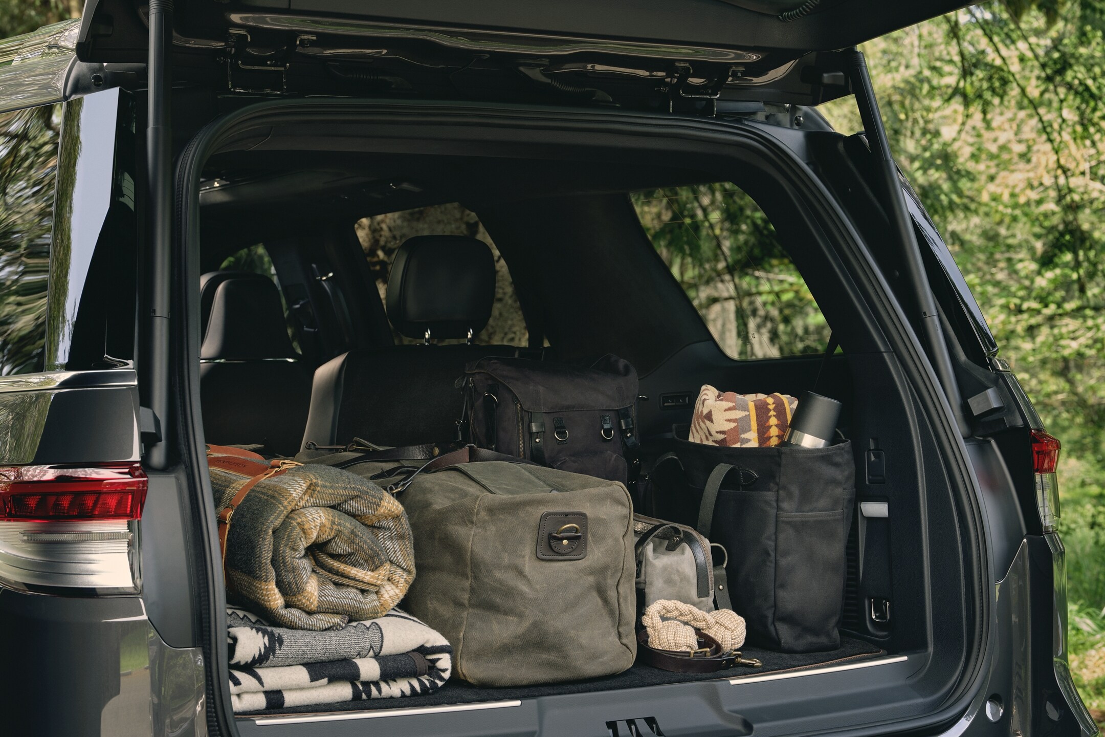 The rear cargo area of a 2024 Lincoln Black Label Navigator SUV is filled with bags, blankets and camping supplies