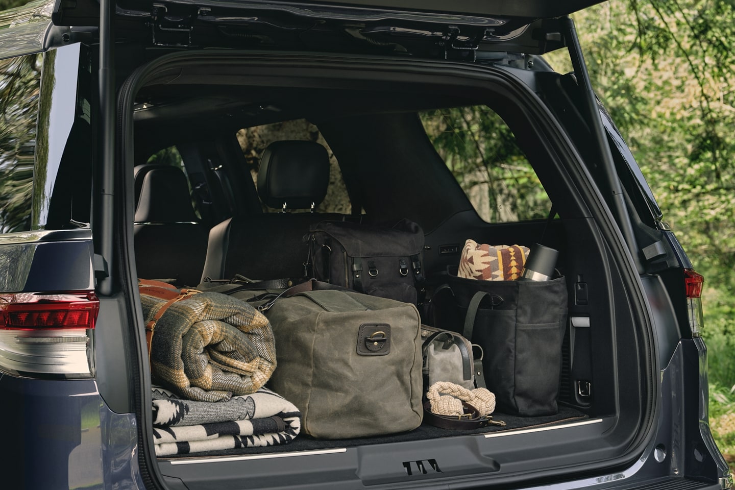     The rear cargo area of a 2023 Lincoln Black Label Navigator® SUV is filled with bags, blankets and camping supplies.