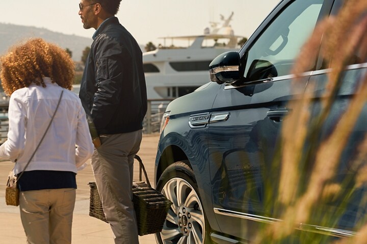 A little girl and dad walk away from a 2023 Lincoln® Navigator SUV with its sideview mirrors folded