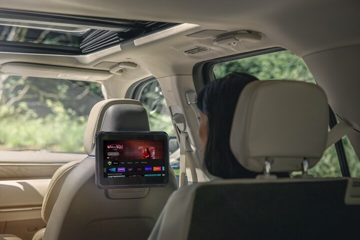 A woman sitting in the second row is looking at a nature scene on the Lincoln Play screen