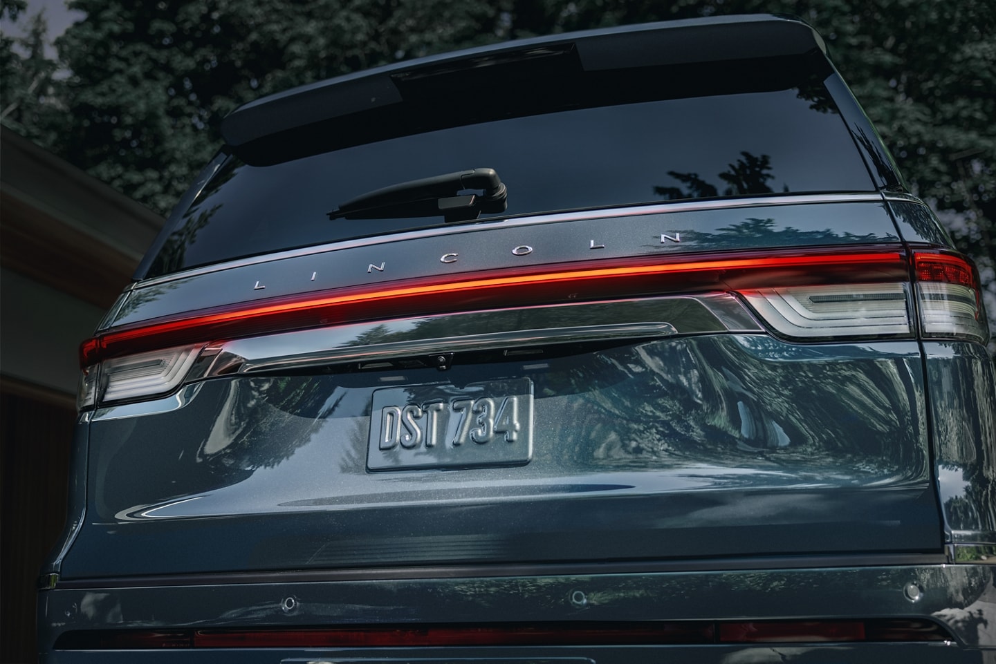 The rear LED taillamps of a 2023 Lincoln Reserve SUV illuminate with a red glow at night
