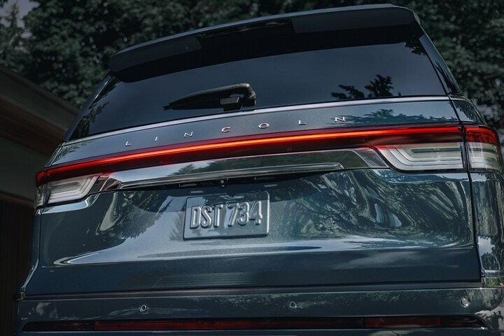 The rear LED taillamps of a 2023 Lincoln Reserve SUV illuminate with a red glow at night